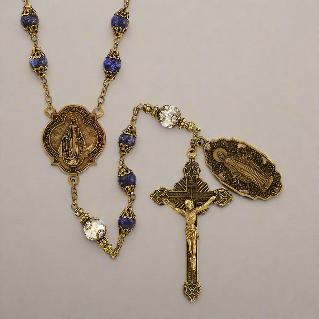 Rosary in antique gold finish featuring both dark blue and crystal beads and two medals featuring Mary, Mother of Jesus. 